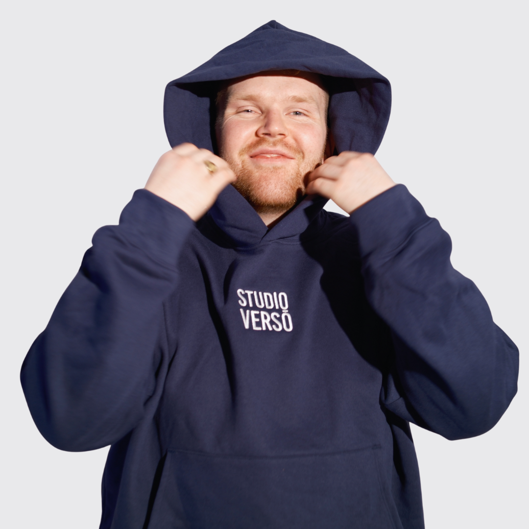 Man wearing a navy blue hoodie with Studio VERSŌ stacked embroidered logo