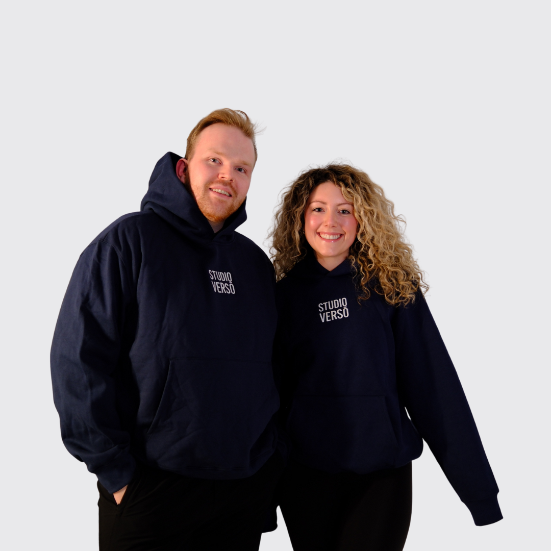 Two people wearing navy hoodies with stacked Studio VERSŌ logo