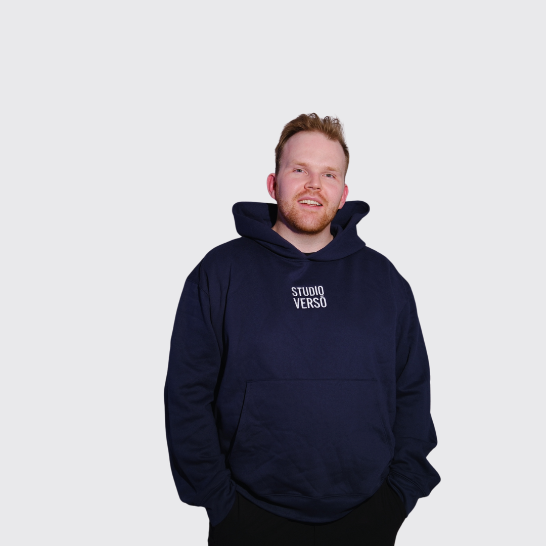 Man wearing a navy hoodie with Studio VERSŌ stacked embroidered logo